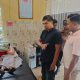 Gambar: Foto menunjukkan seorang pria sedang berbicara dengan seorang petugas polisi di sebuah ruangan rumah sakit. Terlihat seorang perempuan terbaring di tempat tidur di belakang mereka.
