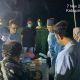 Seorang polisi sedang menyelidiki lokasi kejadian di sebuah ruangan, dengan fokus pada sebuah benda kecil yang tergeletak di lantai.