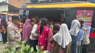 polisi sedang membagikan sayur kepada warga dalam program "Mayur Kamtibmas".