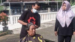 Siswandi sedang mencukur rambut lansia di Graha Lansia Banyuwangi