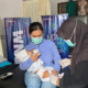 Petugas kesehatan memberikan imunisasi gratis kepada balita dalam kegiatan sosial PNM Banyuwangi untuk cegah stunting.