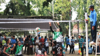 Tim Voli Putri Banyuwangi sedang bermain di lapangan voli. Salah satu pemain sedang melakukan smash, sementara pemain lain bersiap untuk menerima bola.