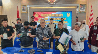 Para petugas dari TNI AL dan kepolisian sedang memaparkan hasil penangkapan imigran gelap di sebuah ruangan. Terlihat sejumlah barang bukti yang diamankan, seperti paspor dan ponsel.