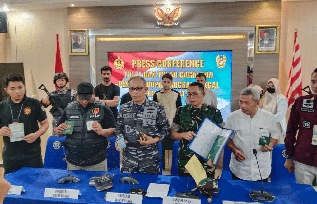 Para petugas dari TNI AL dan kepolisian sedang memaparkan hasil penangkapan imigran gelap di sebuah ruangan. Terlihat sejumlah barang bukti yang diamankan, seperti paspor dan ponsel.