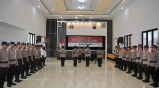 Sejumlah anggota kepolisian berbaris rapi di sebuah ruangan. Terlihat seorang perwira sedang memimpin upacara.