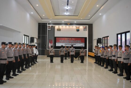 Sejumlah anggota kepolisian berbaris rapi di sebuah ruangan. Terlihat seorang perwira sedang memimpin upacara.