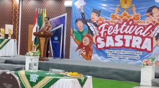 Seorang pembicara di atas panggung sedang memberikan sambutan di hadapan para peserta Festival Sastra di SMK Muhammadiyah 8 Siliragung, Banyuwangi.