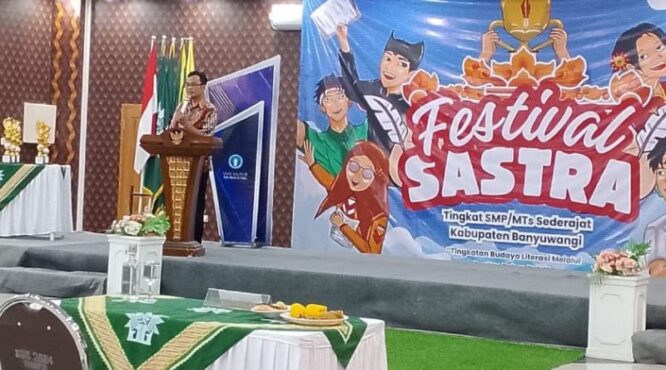 Seorang pembicara di atas panggung sedang memberikan sambutan di hadapan para peserta Festival Sastra di SMK Muhammadiyah 8 Siliragung, Banyuwangi.