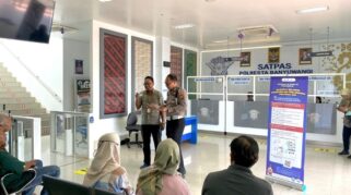 Foto menunjukkan seorang petugas Satpas Polresta Banyuwangi sedang berbicara dengan seorang pria mengenai persyaratan BPJS Kesehatan untuk membuat SIM.