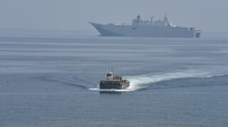 Sebuah kapal perang sedang berlayar di laut. Terlihat kapal perang lain di kejauhan.