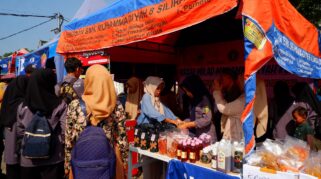 Sejumlah siswa SMK Models sedang menjajakan makanan di sebuah stan bazar. Terlihat berbagai jenis makanan yang tersedia.