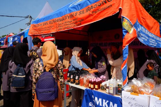 Sejumlah siswa SMK Models sedang menjajakan makanan di sebuah stan bazar. Terlihat berbagai jenis makanan yang tersedia.