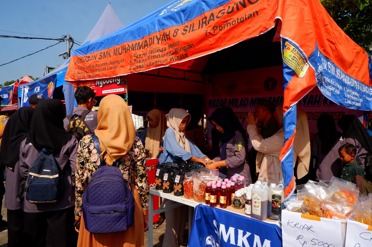 Kuliner Signature Odeng SMK Models Jadi Daya Tarik Pengunjung Bazar Milad Muhammadiyah Ke-112 Sejumlah siswa SMK Models sedang menjajakan makanan di sebuah stan bazar. Terlihat berbagai jenis makanan yang tersedia.