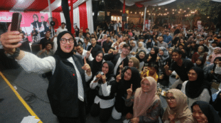 Foto menunjukkan Ipuk Fiestiandani sedang berbicara dengan sekelompok anak muda di depan sebuah panggung.