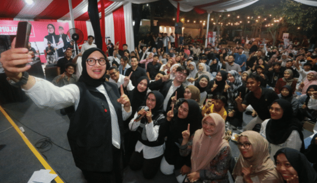 Foto menunjukkan Ipuk Fiestiandani sedang berbicara dengan sekelompok anak muda di depan sebuah panggung.