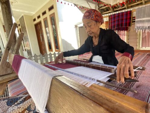 Siyami sedang menenun kain tenun Osing.