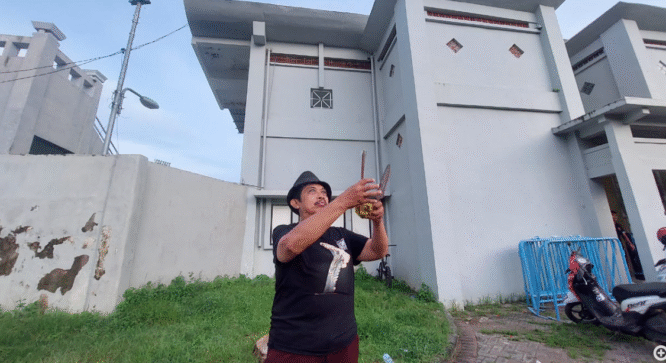 KRT Ilham Triadi Nagoro, pawang hujan, sedang melakukan ritual di dekat Stadion Diponegoro Banyuwangi.