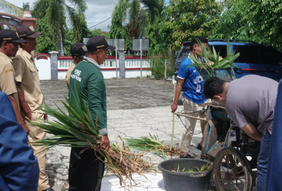 Mahasiswa KKN UNAIR membantu warga Desa Purwoagung mencacah rumput untuk pakan ternak.