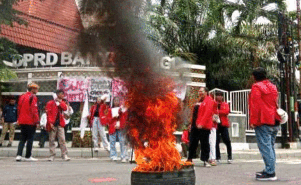 Puluhan mahasiswa berdiri membawa poster tuntutan revisi anggaran pendidikan di depan gedung DPRD Banyuwangi.