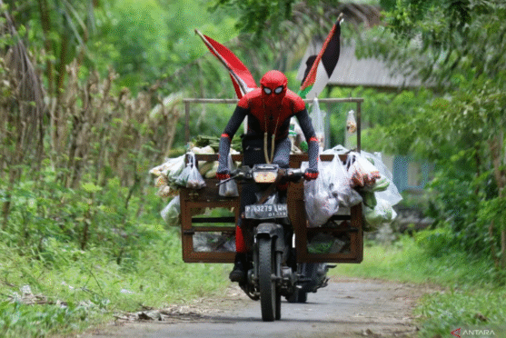 Suaidi, pedagang sayur dengan kostum Spiderman, sedang berjualan di Banyuwangi.
