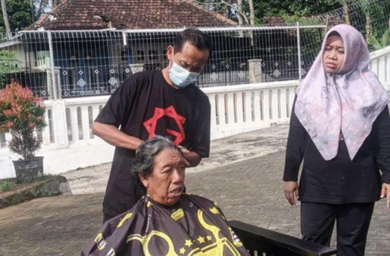 Siswandi sedang mencukur rambut lansia di Graha Lansia Banyuwangi