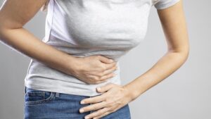 Ilustrasi perempuan mengalami sakit perut akibat ISK dan gangguan pencernaan