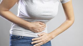 Ilustrasi perempuan mengalami sakit perut akibat ISK dan gangguan pencernaan