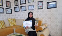 Cici Arista Devi menunjukkan piala dan sertifikat Juara I Lomba Menulis Artikel PDNA Banyuwangi di ruang prestasi SMK Muhammadiyah 8 Siliragung.